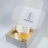 Custom printed white tear strip mailer box with inner Dermacare DNA logo, filled with skincare bottles, cream jar, shredded paper and thank you note, light grey background wholesale cosmetic shipping packaging