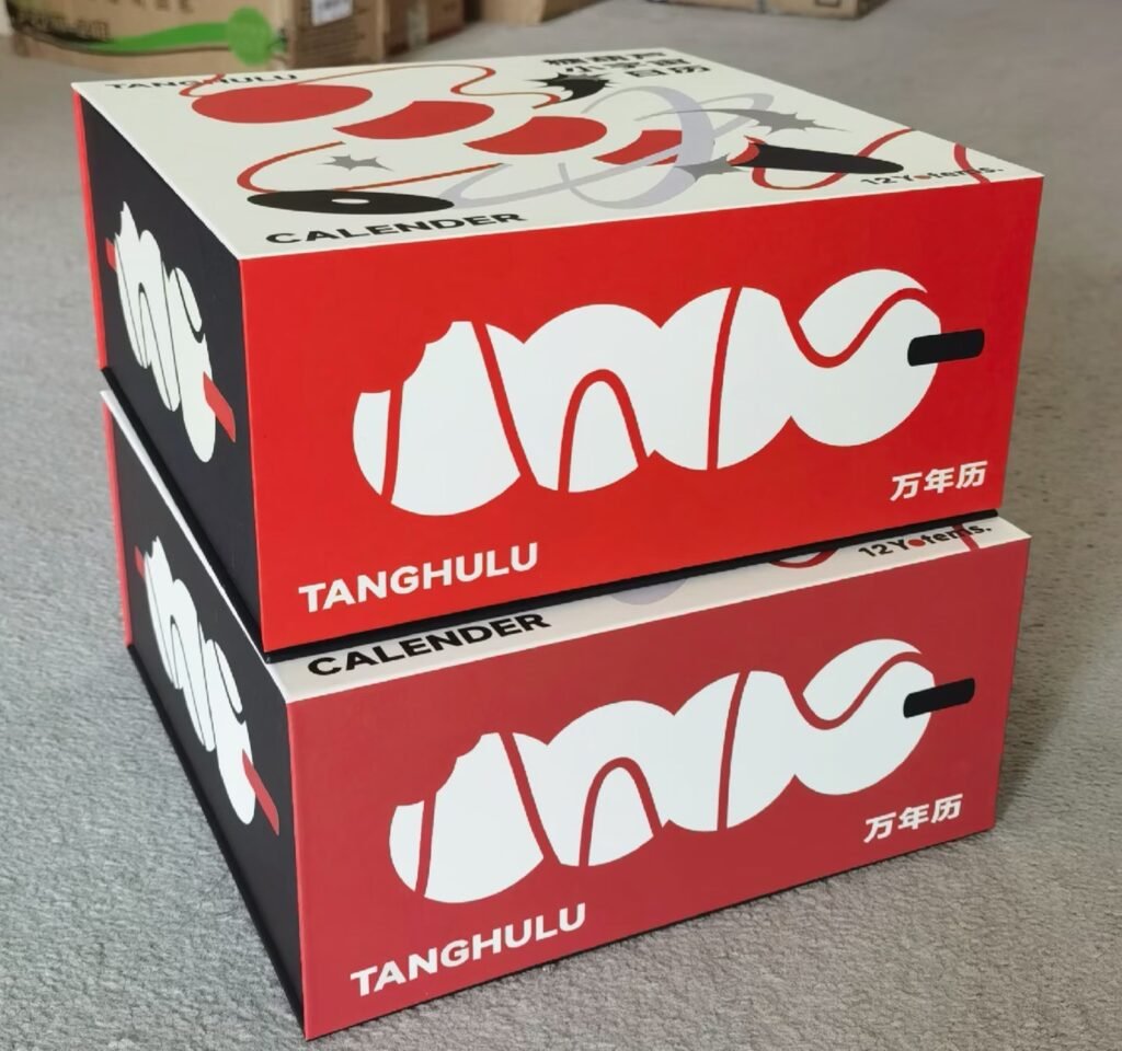 Two custom printed packaging boxes stacked, Tanghulu calendar product box with bold red graphic design, custom retail box sample for brand packaging